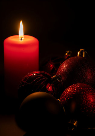 A single red candle burning brightly next to christmas ornamentsの素材