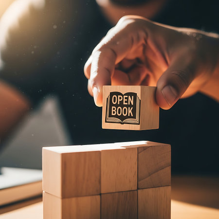 Hand placing wooden block with open book stamp on towerの素材