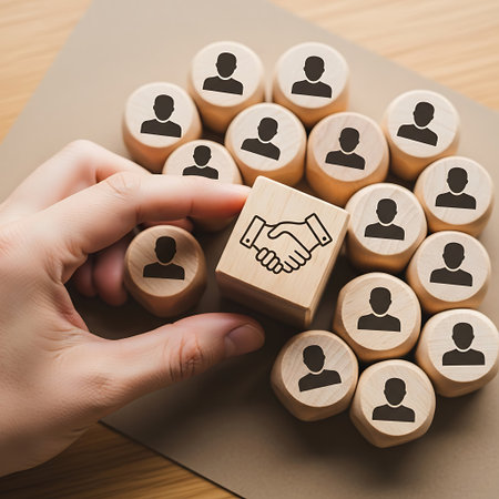 Hand placing wooden block with handshake among people iconsの素材