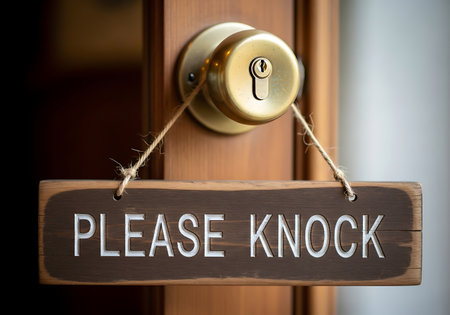 Wooden sign with the words please knock hanging on a wooden door near a knobの素材