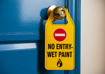 Yellow wet paint no entry door hanger sign on bright blue doorの素材
