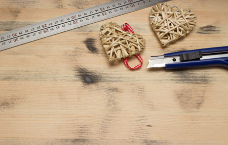 Two straw heart, steel ruler and knife on wooden backgroundの写真素材