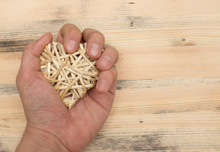 straw heart  in hand on light wooden backgroundの写真素材