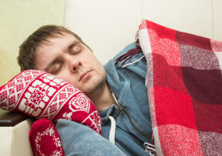 Man with high temperature sleeping on the sofaの写真素材