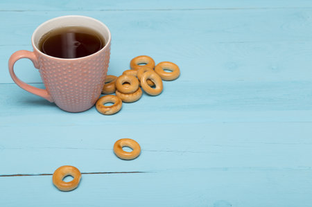 cup of hot tea with bagels on a blue wooden backgroundの写真素材