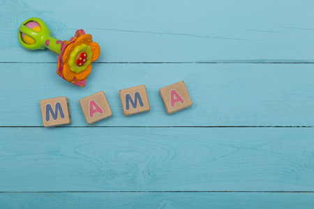 children's blocks with letters mother and rattle on a blue wooden backgroundの写真素材