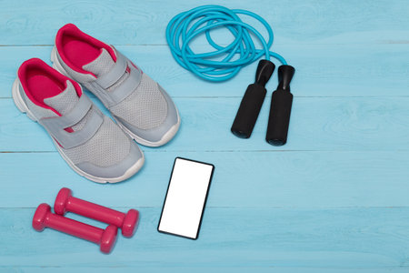 sneakers, weights, phone and a jump rope on blue  woodenbackgroundの写真素材