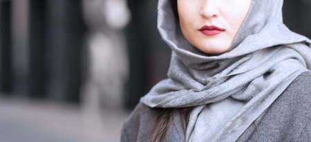 Attractive brunette with red lipstick  in grey shawl outdoors in springの写真素材