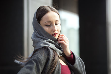 Attractive brunette with red lipstick  in grey shawl outdoors in spring