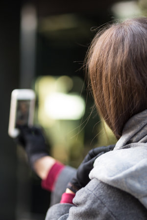 Portrait of a beautiful young woman selfie in the center of the city with white smartphoneの写真素材