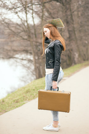Woman with travel suitcase androad map standing on the road in park