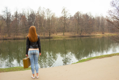 Woman with travel suitcase androad map standing on the road in park