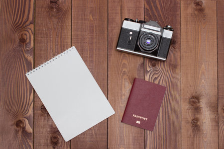 Travel concept - empty notepad, retro camera and passport on brown wooden background. Prepare for journey. Copy space for your text.の写真素材