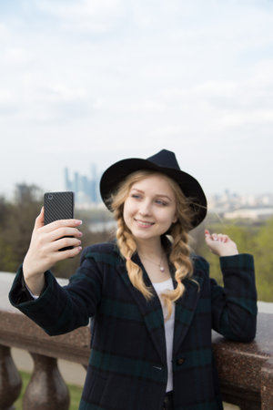 Happy selfie tourist young woman taking a self-portrait photo with smartphone app in front of skyscrapers.の写真素材