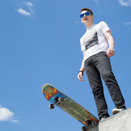 Skater boy standing  at skatepark ramp, sky backgroundの写真素材
