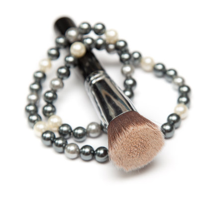 Pearl black and white necklace and make-up brush on it in closeupの写真素材
