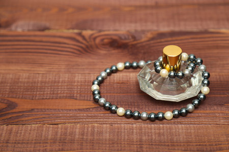 Perfume bottle and pearl necklace on brown wooden backgroundの写真素材