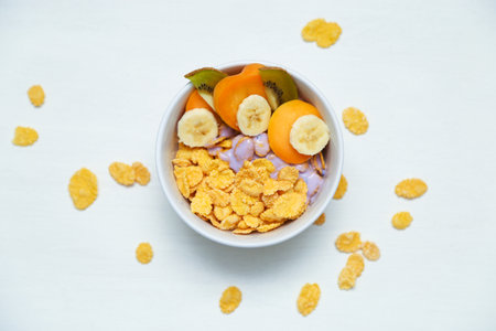 Muesli with blackberry yoghurt, fruits peach, banana, kiwi in white plate. Healthy breakfast, still life food.の写真素材