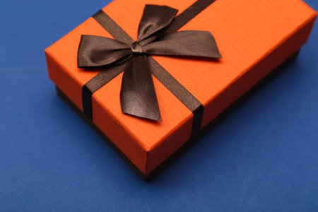 orange gift box with brown bow on a blue background, father's day concept