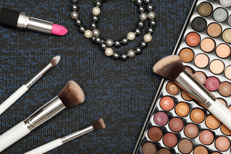 Make up set on black and blue background. Eyeshadow palette, brushes and pink lipstick.の写真素材