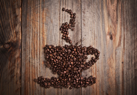 Coffee beans in cup shape on the old wooden  backgroundの写真素材