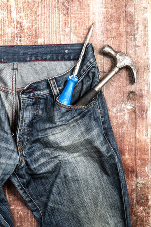 Set of different old tools in a blue jeans pocket on grungy wooden backgroundの写真素材