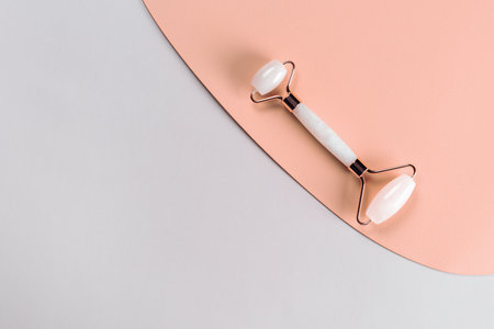 Jade facial massager on pink background. Smooth facial skin. Facial massage.の写真素材