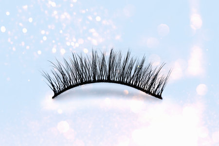 Pave eyelashes on blue background. Female cosmetics. Extension and lengthening of eyelashes.