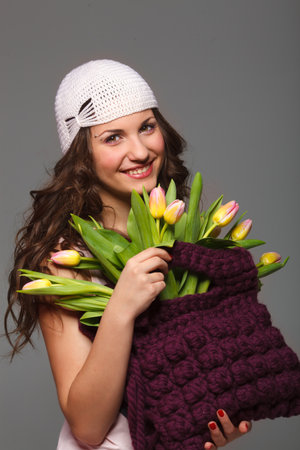 Pretty young woman with long hair wearing a handmade hat and bag with tulipsの写真素材