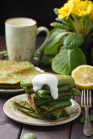 pancakes with spinach and sour cream on wood table.の写真素材