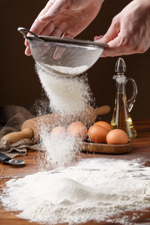 Sifting flour with flour filter. Making cookies A chef making cookies. The first step in cooking dumplings. Womans hands sifting flour through a sieve for baking. Chefs Hands Sifting Flour.の写真素材