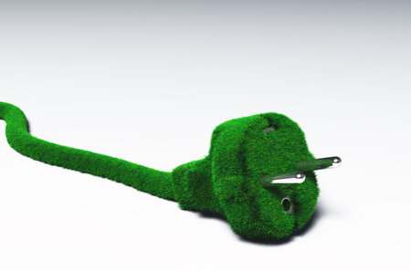 closeup of a cabled plug covered by green and fresh grass that lays on a white groundの写真素材