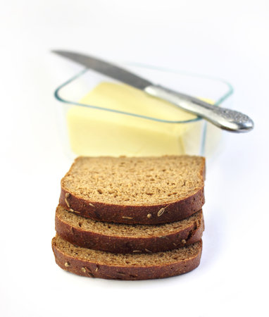 Slices of rye bread and butter in a glass container on background