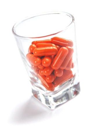 Orange pill capsules in glass on white backgroundの写真素材