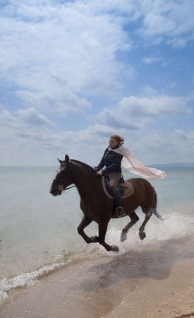 Girl on a horse galloping along the beachの写真素材