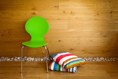 Green Chair and colorful pillows against wooden wall / Modern interiorの写真素材