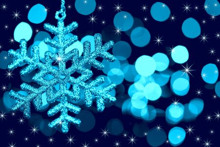 Christmas decoration snowflake  on defocused lights and stars background / blue tonedの写真素材