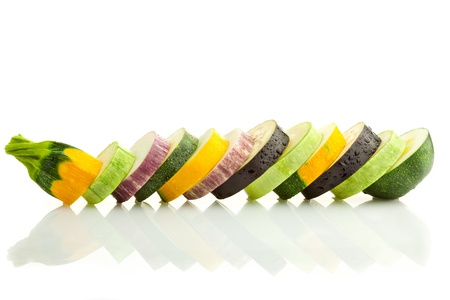 Different kind of courgettes (zucchini) and eggplants / colorful slices / horizontal border isolated on white with real reflectionの写真素材