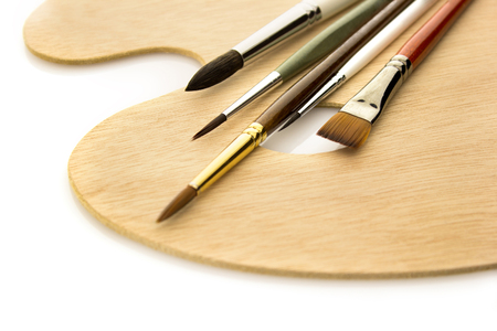 Art color brushes on wooden natural palette isolated on white backgroundの写真素材