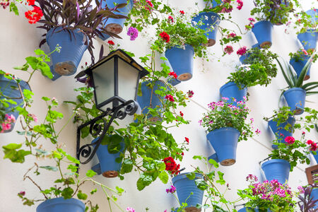 Blue Flowerpots and Flowers on a white wall with vintage lantern. Old European Town, Spainの写真素材