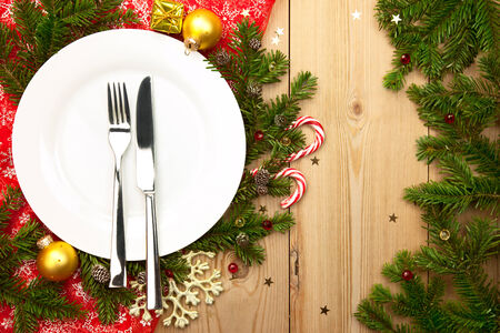 Christmas  Dinner  - white plate with decorations on wooden background with firtree and baublesの写真素材