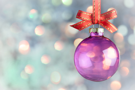 Christmas Decoration Beautiful magic bokeh with purple bauble and red ribbon over  light backgroundの写真素材