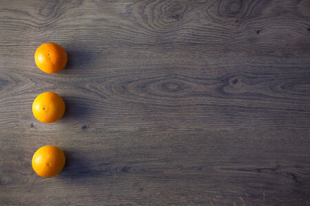 Three Oranges are on empty dark Wooden Table with copy spaceの写真素材