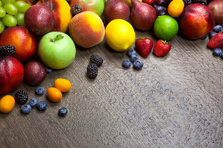Border of mixed fruits with water drops on beautiful wooden texture - copy spaceの写真素材