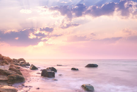 Sunrise landscape over beautiful rocky coastline in the Sea with sunbeams and cloudsの写真素材