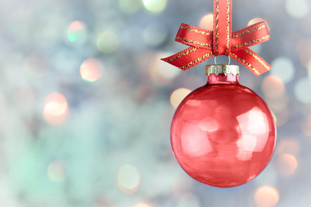 Christmas Decoration - Beautiful magic bokeh with red  bauble and bow over light backgroundの写真素材