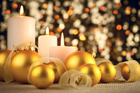 Warm Christmas glitter bokeh background with candles, baubles and ribbonsの写真素材