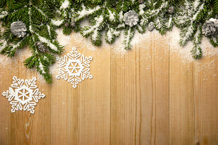 Christmas background with fresh firtree, decorative snowflakes and cones on wood with bright snowの写真素材