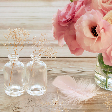 Still life with pink flowers in a vase with fearher and two glass botles - vintage lookの写真素材