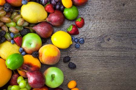 Mixed fresh Fruits on the dark wooden table with water dropsの写真素材